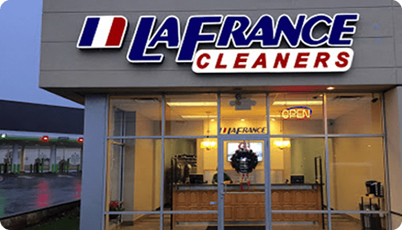 Storefront of LaFrance Cleaners with large illuminated signage, glass windows, and an open sign displayed inside.